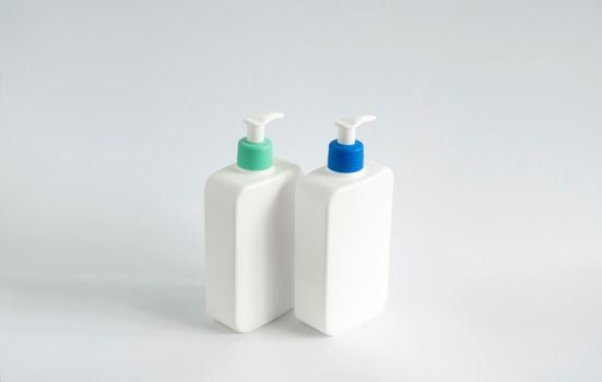 Two white unbranded dispenser bottles on white background. Cosmetic packaging mockup with copy space