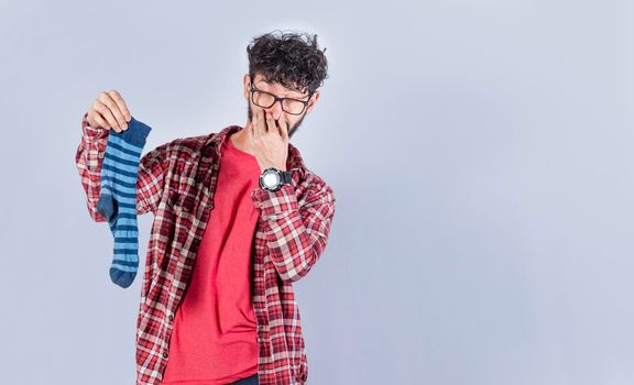 A man with a sock in his hand covering his nose, a guy with a stinky sock in his hand, smelly socks concept