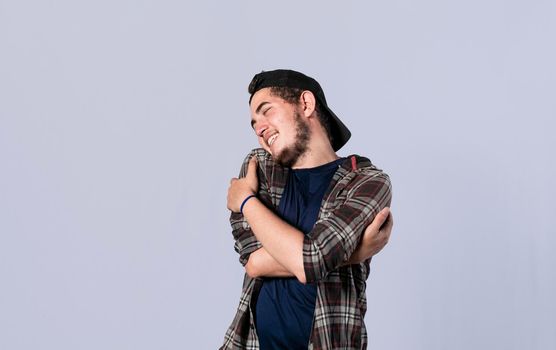 Friendly man hugging himself, Pleased young man hugging himself, Attractive positive looking friendly young man with a sincere smile embracing himself gratefully
