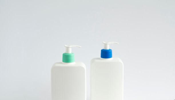 Two white unbranded dispenser bottles on white background. Cosmetic packaging mockup with copy space