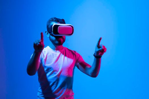 Bearded man playing VR video game in metaverse with virtual reality goggles and trying to touch something. Future technology concept