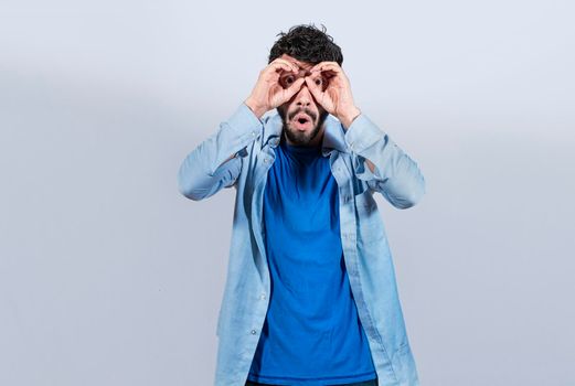 Curious man making binoculars gesture, Guy on isolated background making binoculars gesture, Man making binoculars gesture, man using his fists as binoculars