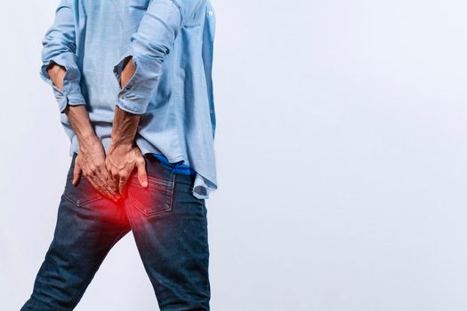 Man with digestive problem touching his buttock, man with hemorrhoid problem on isolated background, Man with diarrhea problem