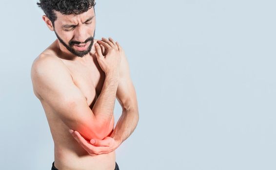Person with elbow pain, concept of a man with elbow pain from rheumatism, shirtless man massaging sore elbow, man with elbow cramp