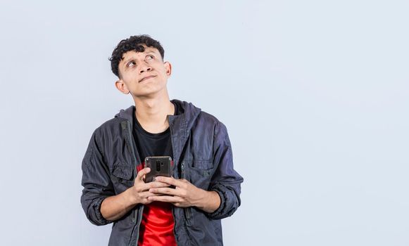 thoughtful guy with cell phone in hand, handsome latin guy thinking with cell phone in hand