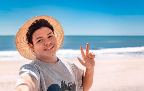 Young man taking a selfie portrait on the beach, handsome boy taking a selfie on the beach