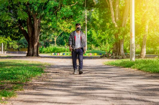 Man walking in the street with face mask on, man walking head-on in the street with face mask, young man with mask walking down the street