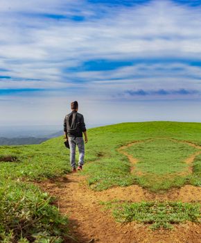 A backpacker walking on a hill with blue sky and copy space, man backpacking on a hill and blue sky background with copy space, successful man concept.
