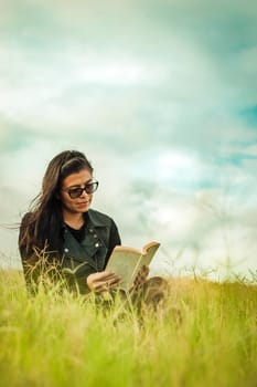 Woman reading in the field, girl reading a book with copy space
