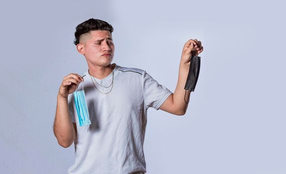 Man deciding to wear surgical mask, Latin man deciding to wear surgical mask on isolated background
