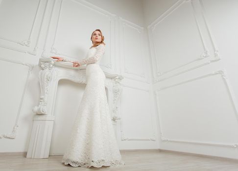 Full-length portrait of young gorgeous bride posing in antique interior.