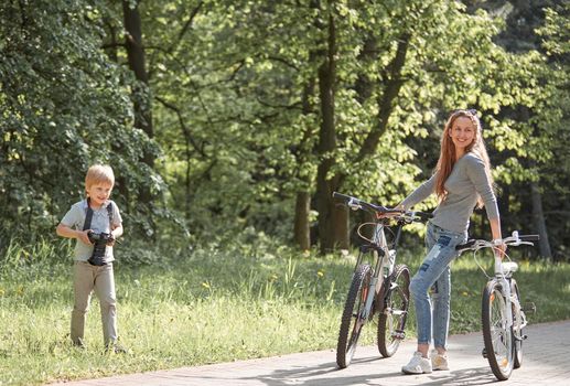 little boy takes pictures of his mother while walking in the Park. the concept of family happiness