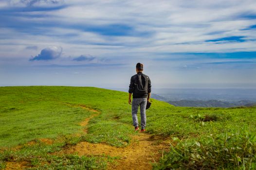 A backpacker walking on a hill with blue sky and copy space, man backpacking on a hill and blue sky background with copy space, successful man concept.
