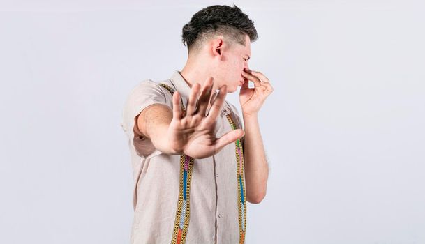 Confused unhappy man grabbing nose with fingers and stretching hand out feeling disgusted, A man with covering his nose