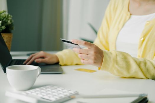 Close up woman using credit card for purchasing and shopping online on laptop computer.