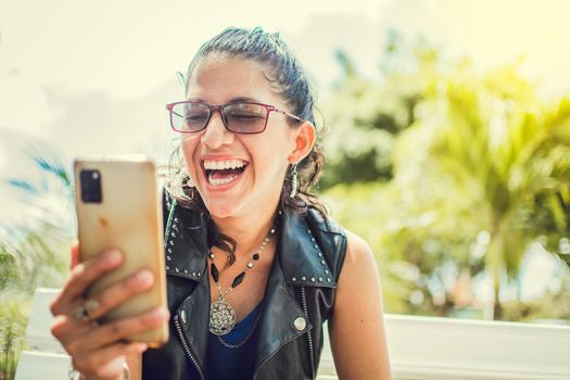 Close up of a happy girl checking her cell phone, Happy woman sitting with her cell phone outside, cell phone, Happy woman sitting on a bench sending a text message