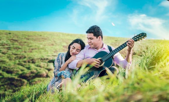 Man playing guitar to a girl, A woman leaning on the shoulder of a young man, man with woman in the field playing guitar