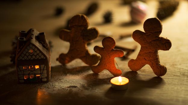 Christmas gingerbread men candles with cinnamon stars Pine twig Christmas ball on a wooden floor