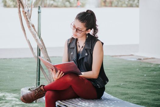 A student girl reading a book, urban girl sitting on a bench reading a book, Latin girl reading a book outside 