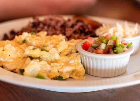 Gallopinto breakfast served on wooden table, gallopinto with fried eggs with pico de gallo on wooden table