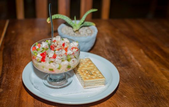 Shrimp cocktail served on wooden table, close up of a shrimp cocktail with crackers on wood