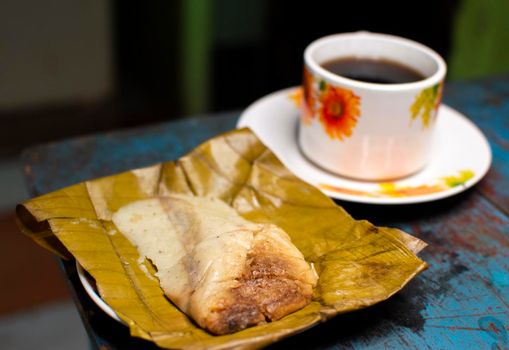 Stuffed tamale served on wooden table, stuffed tamale on banana leaf served on wooden table, typical nicaragua food