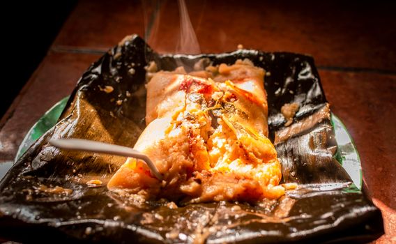 Nacatamal served in banana leaf, Close up of Nicaraguan nacatamal, Typical Nicaraguan food El nacatamal, Typical Nicaraguan food