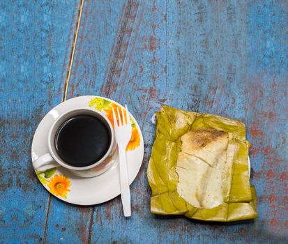 Stuffed tamale served on wooden table, stuffed tamale on banana leaf served on wooden table, typical nicaragua food