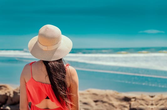 woman in hat from back to the sea, girl in hat looking to the sea, vacation concept, rear view of a girl watching the sea