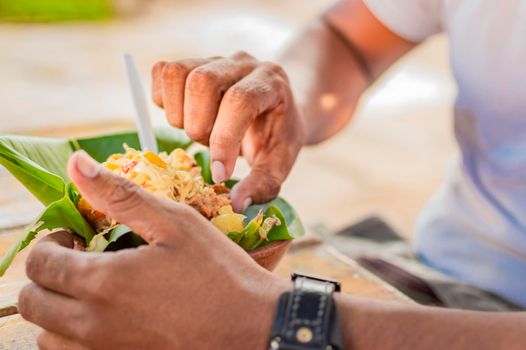 Close-up of a person eating vigoron, person eating vigoron on a wooden table