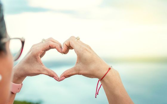 Hands together in a heart shape, woman's hands together in a heart shape, hands making a heart shape