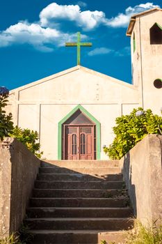 Front view of the entrance of a church, view of the entrance of a church with the cross on the roof