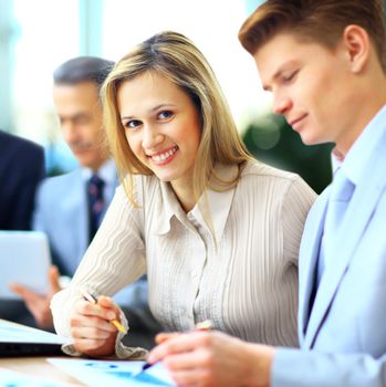 Smiling businesswoman posing while colleagues talking together in bright office