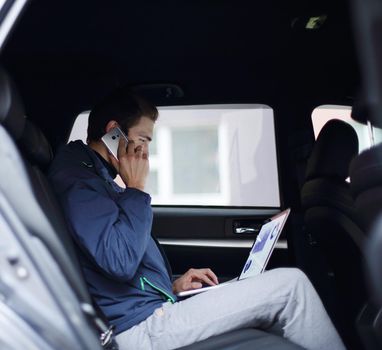 closeup. business man uses a laptop and mobile phone sitting in the car