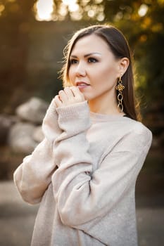 Cute young woman in a sweater in the autumn forest among the trees outdoors. High quality photo