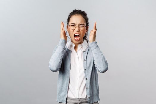 Emotions, people and lifestyle concept. Aggressive young annoyed asian woman have emotional working burnout, screaming with hate and rage, staring furious grimacing, shaking hands in anger.