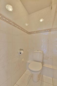 Interior of narrow restroom with sink and wall hung toilet with white walls and checkered floor
