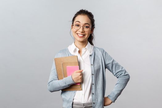 Education, teachers, university and schools concept. Upbeat happy female tutor likes teaching students, standing enthusiastic with prepared study material, hold notebooks smile broadly.