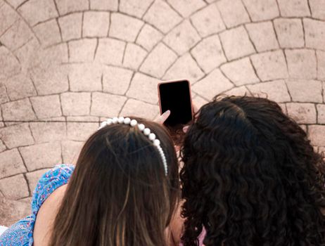 friend showing her cell phone screen, two girls pointing at her cell phone, Girl showing her smartphone to her friend