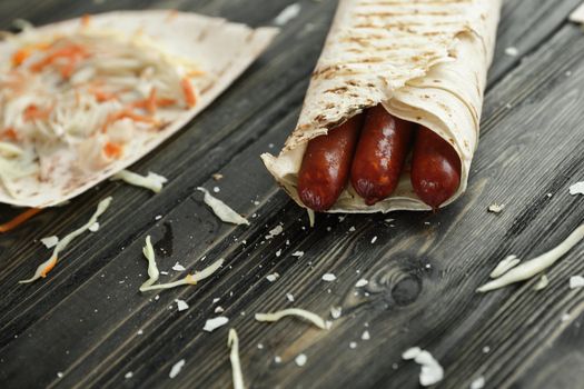 spicy sausages in pita bread on a wooden table.