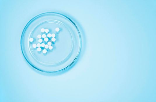 White pills on glass tray on blue background , hearth care  and medicine