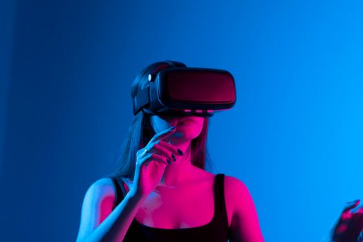 Young attractive brunette woman wearing VR goggles and enjoying amazing experience playing and having fun in virtual reality video game