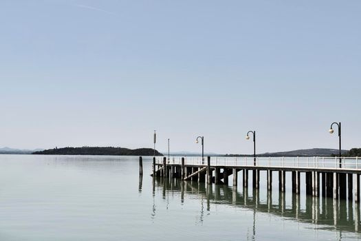 Lake Trasimeno , Italy , pier over water in Passignano sul Trasimeno  , in the background coastline