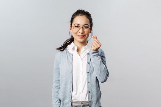 Emotions, people and lifestyle concept. Optimisic cute asian woman, young tutor in glasses entertain small kids during classes online education school, show korean heart sign and smile.