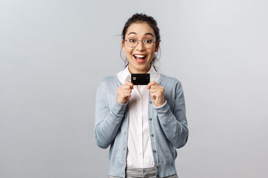 Technology, online purchases and finance concept. Excited happy asian woman in glasses, showing black credit card with smiling upbeat face, shopping in internet, pay for delivery.