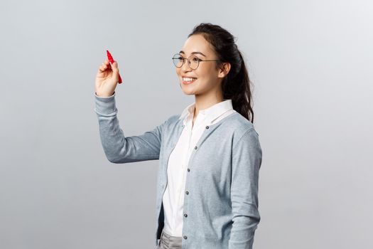 Teaching, online education and lifestyle concept. Young smiling smart student, tutor explain lesson material, solving exercise over blackboard, writing with red marker in air.
