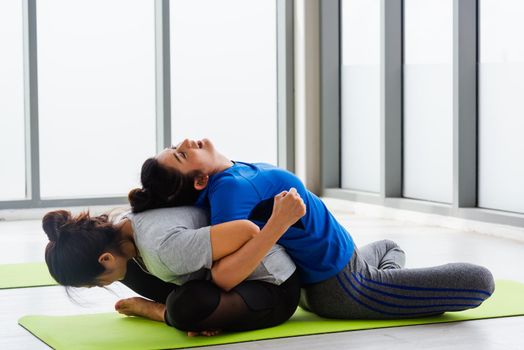 Two Asian women sporty attractive people practicing yoga lesson together, working out at the fitness GYM, Young and senior female exercising do yoga in yoga classes, sport healthy lifestyle