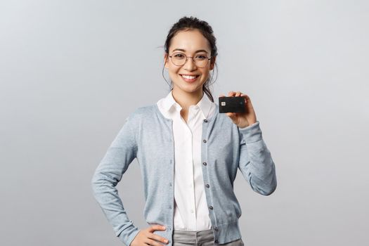 Technology, online purchases and finance concept. Cheerful, friendly-looking young asian woman recommend bank, using credit card to pay for delivery or shopping in internet during lockdown.