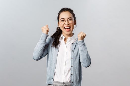 Super cool news, good for you. Optimistic, supportive asian girl encourage friend, watching sports game and rooting for team, chanting and smiling, triumphing from success, celebrate victory.