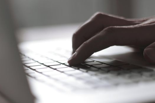 close up. blurred image of male hand typing on laptop keyboard.